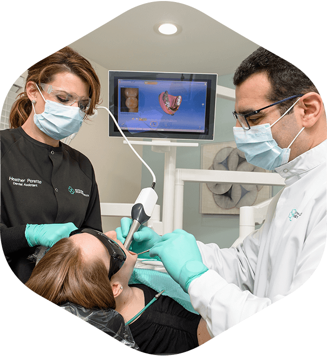 Dr. Khayat, a Hingham dentist, and a member of his dental team perform a dental procedure on a patient 